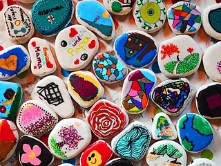 Viele bunte, bemalte Steine mit verschiedenen Motiven.