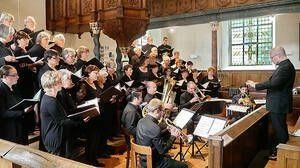 Ein Chor und Orchester treten in einer Kirche auf, dirigiert von einem Mann.